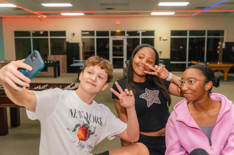 Three teenagers taking a selfie at the Orlando YMCA during the Teen Nights program