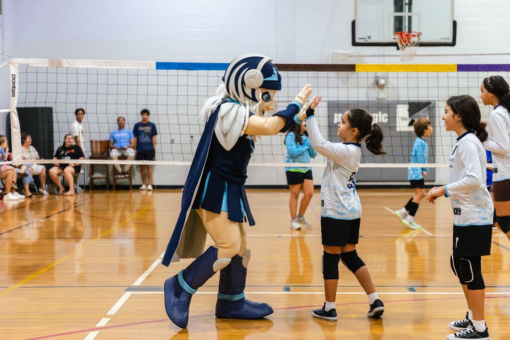 Orlando Valkyries mascot high-fiving a YMCA Jr. Valkyries volleyball league player